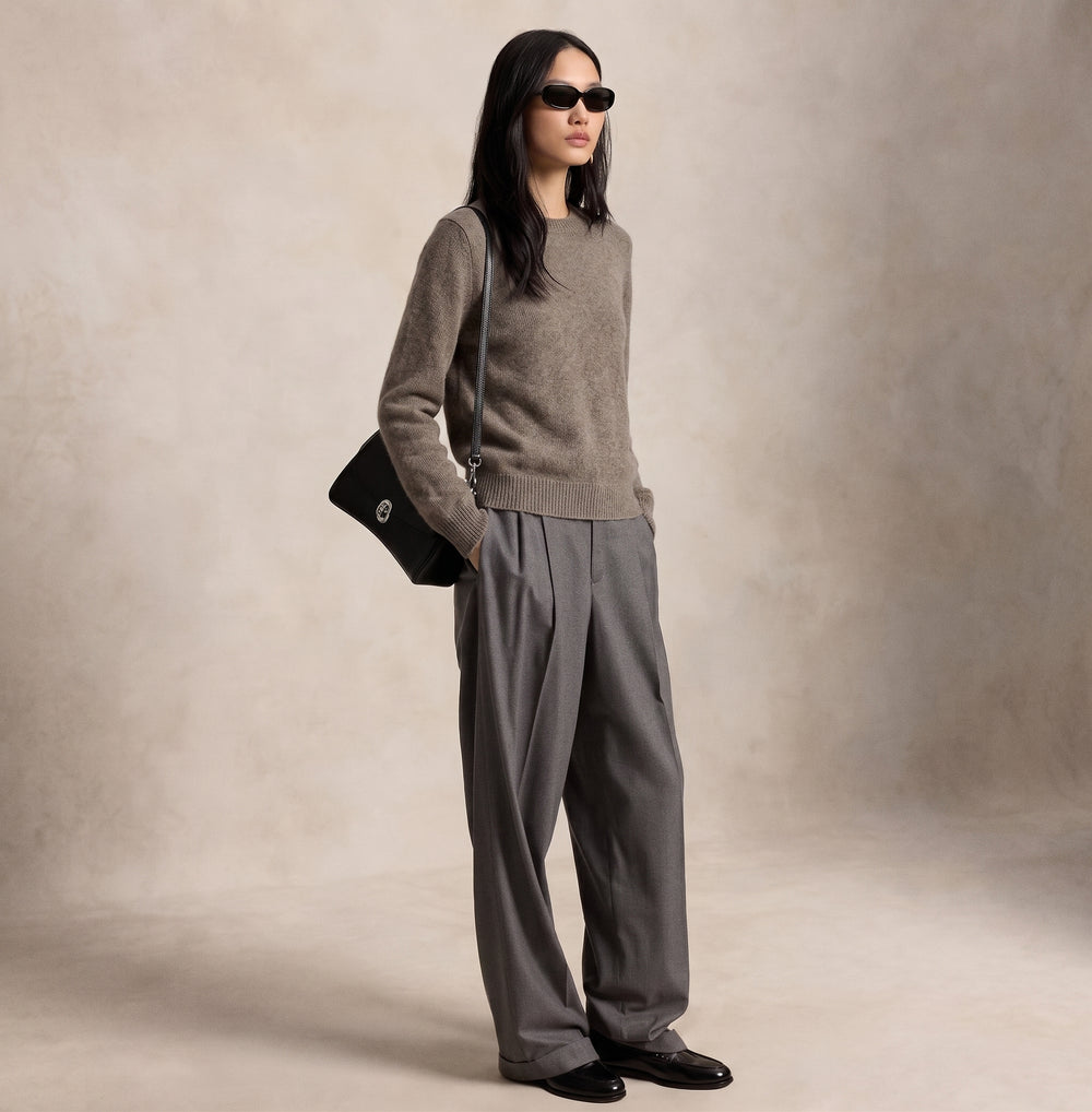 A model wearing an Avelyn knit sweater with tailored trousers