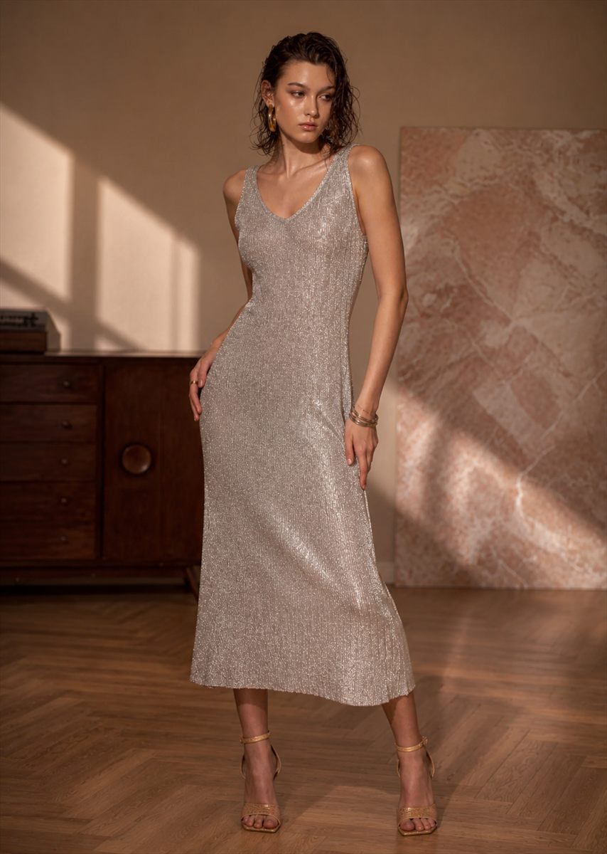 Model in a silver metallic knit slip dress in a sunlit room